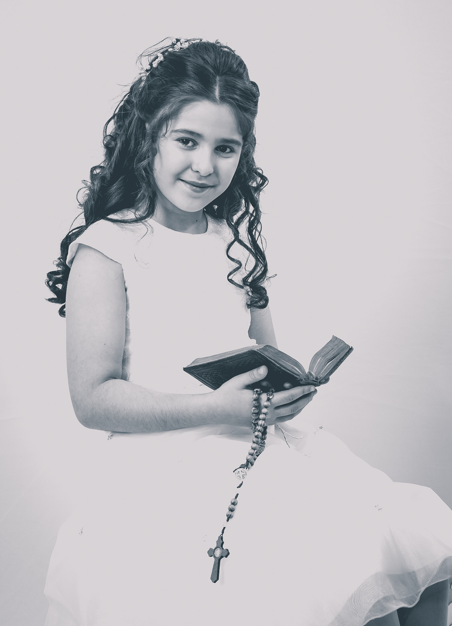Jeune fille en robe de première communion tenant un chapelet et un livre de prière