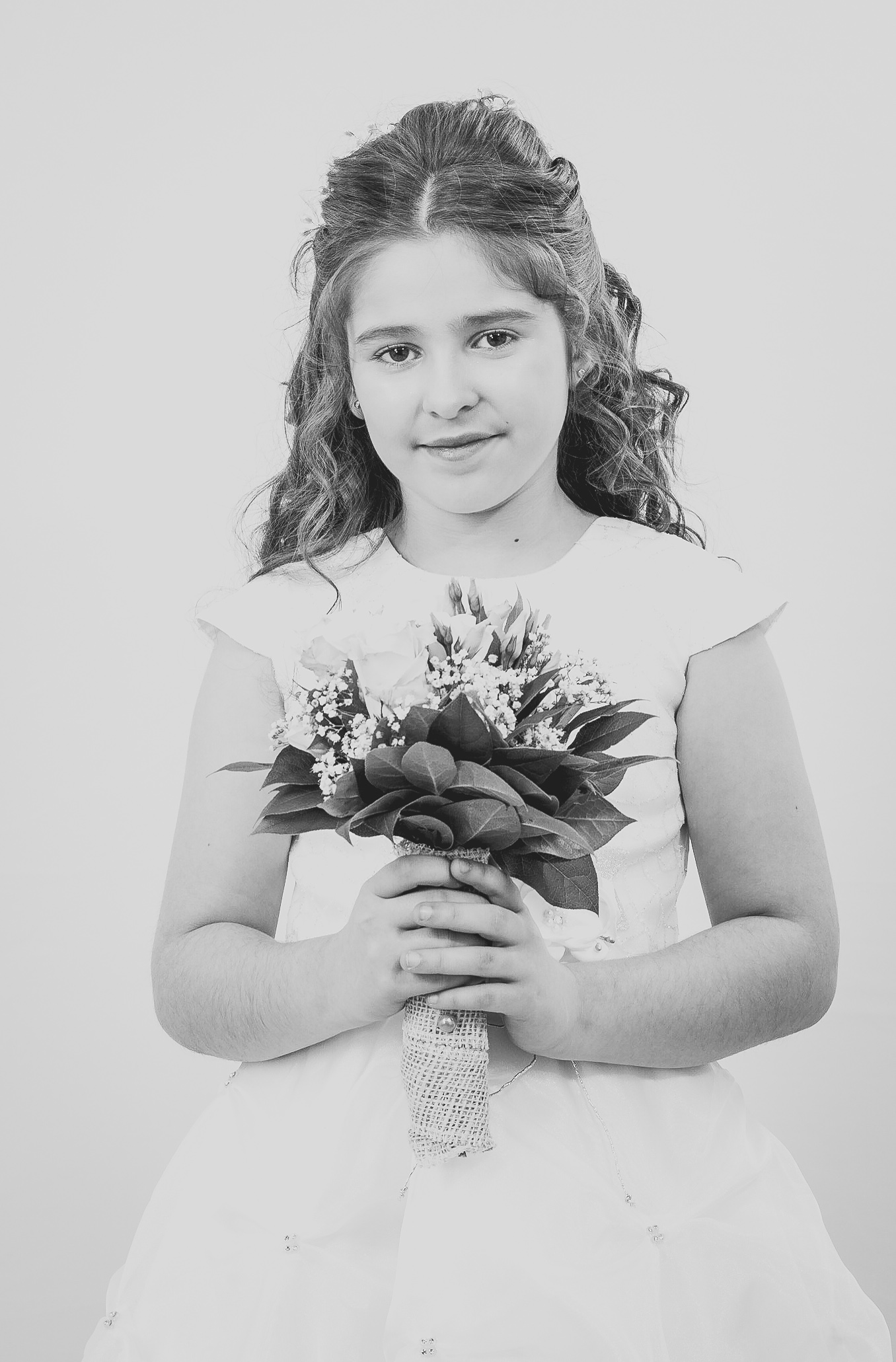 Jeune fille en robe de première communion tenant un bouquet de fleurs