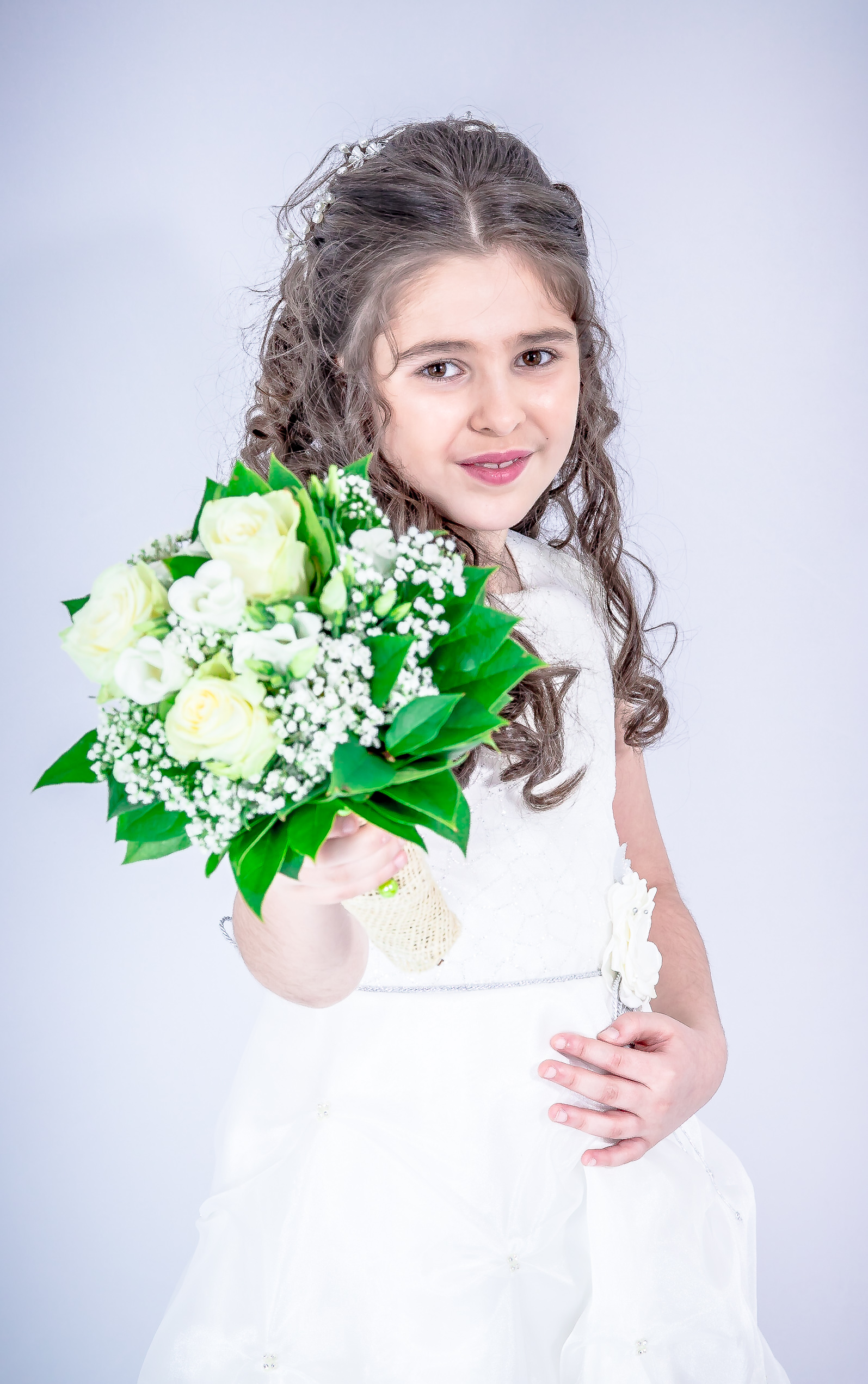 Jeune fille en robe de première communion tendant son bouquet vers l’objectif