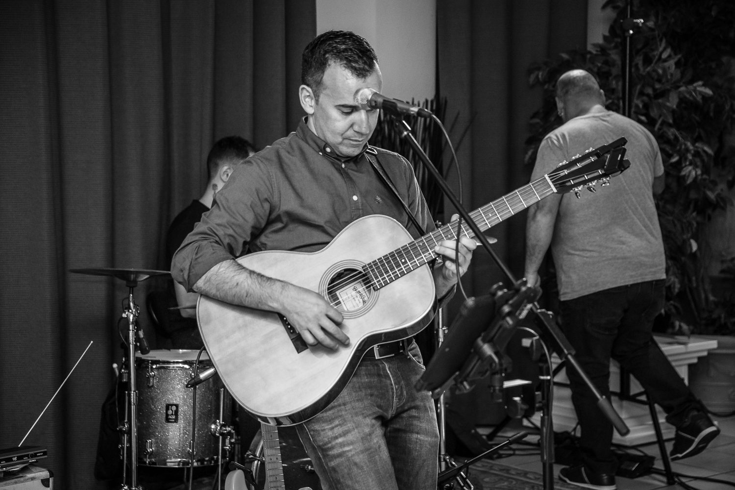 Guitariste chantant au micro, batteur en arrière-plan