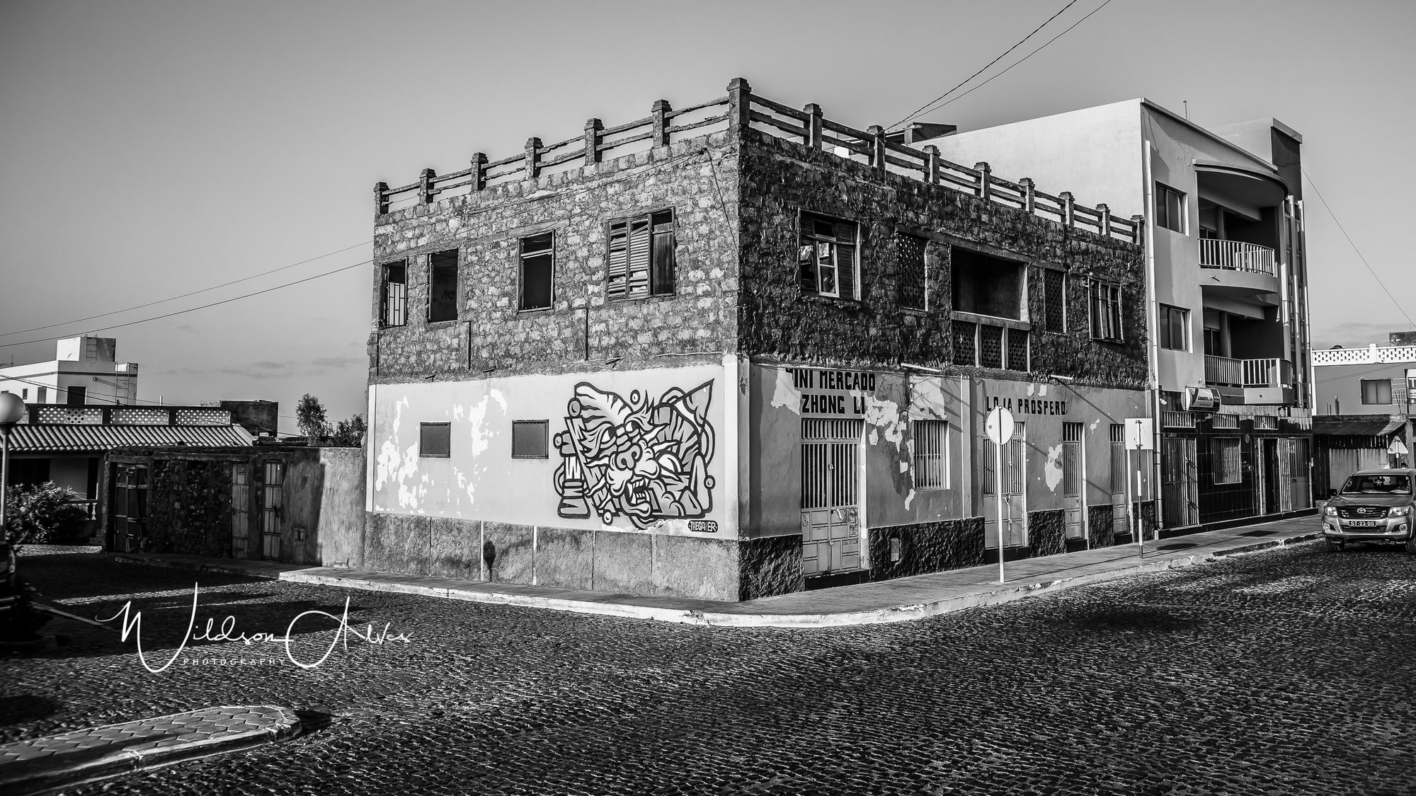 Bâtiment en pierre avec graffiti, rue pavée, noir et blanc
